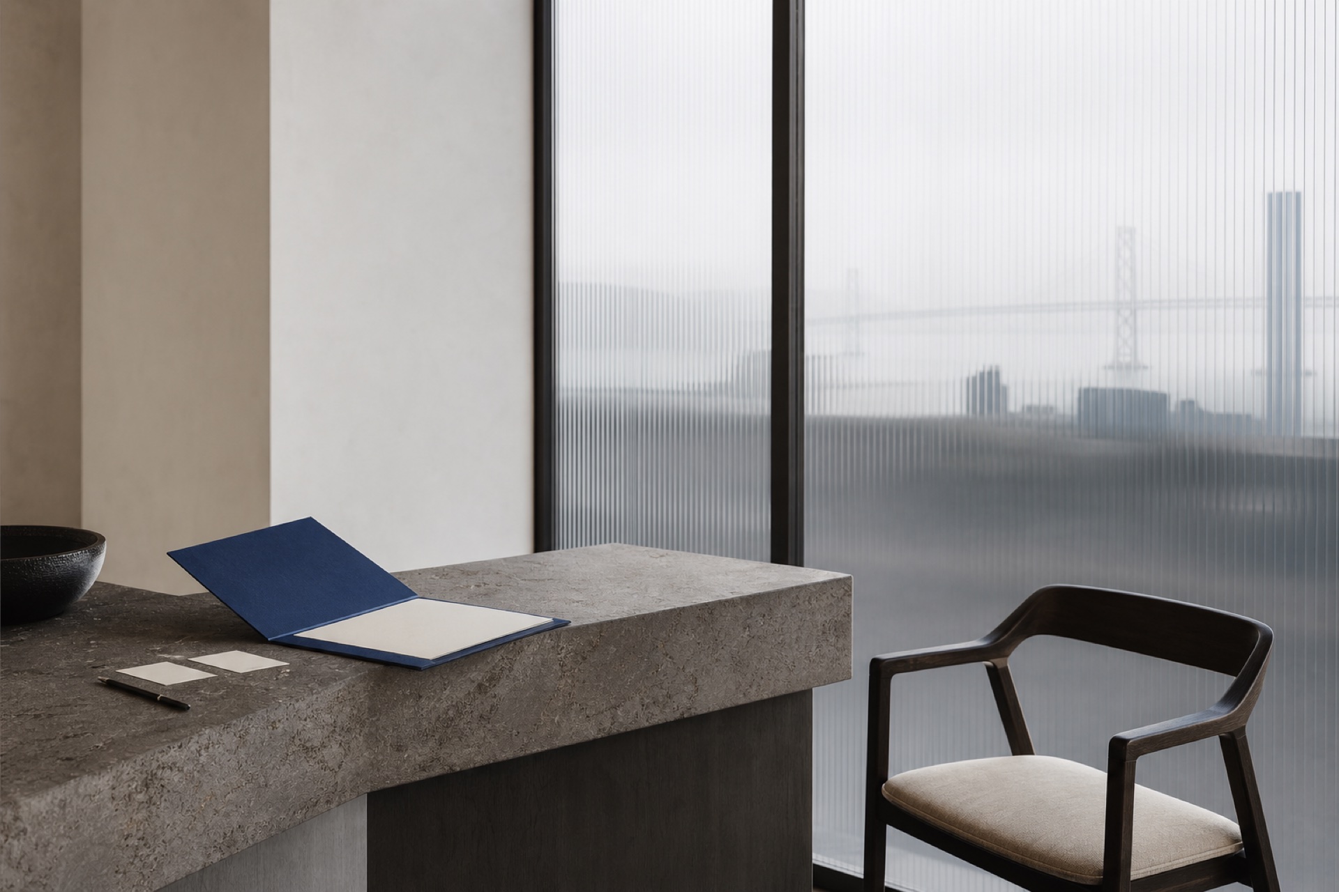 A quiet briefing counter with a cobalt folio and guest chair